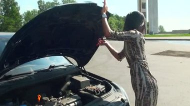 esmer bir arabanın kaputu açar