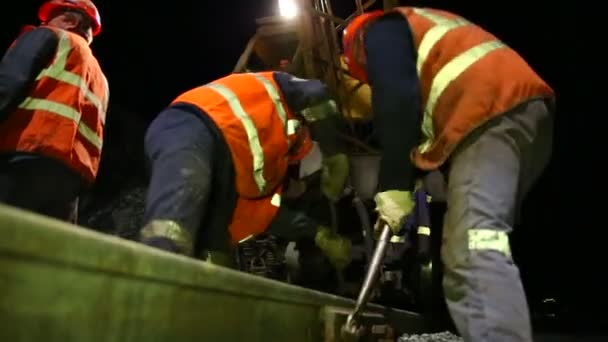 Железнодорожники прикручивают рельсы к балласту — стоковое видео