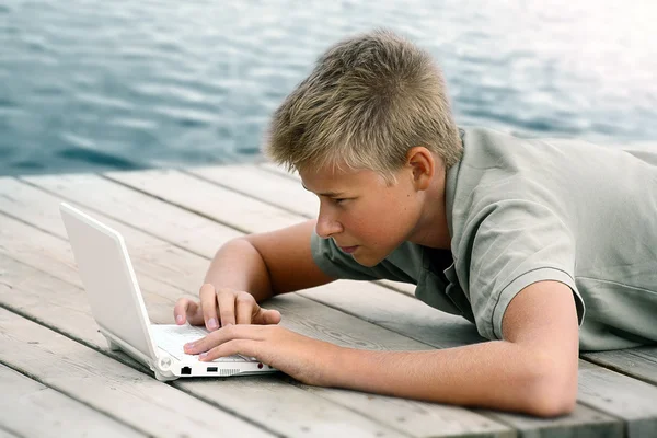 Menino escrevendo com computador no mar — Fotografia de Stock