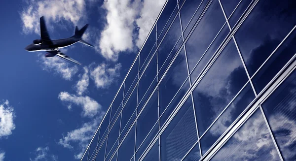 Avião voando sobre edifícios de escritórios altos — Fotografia de Stock