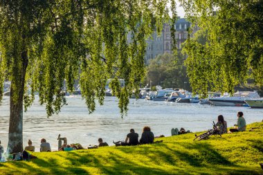STOCKHOLM, SWEDEN - MAJ 11, 2015: Curgarden 'da akşam, parkta yeşil çimenler, dinlenen insanlar