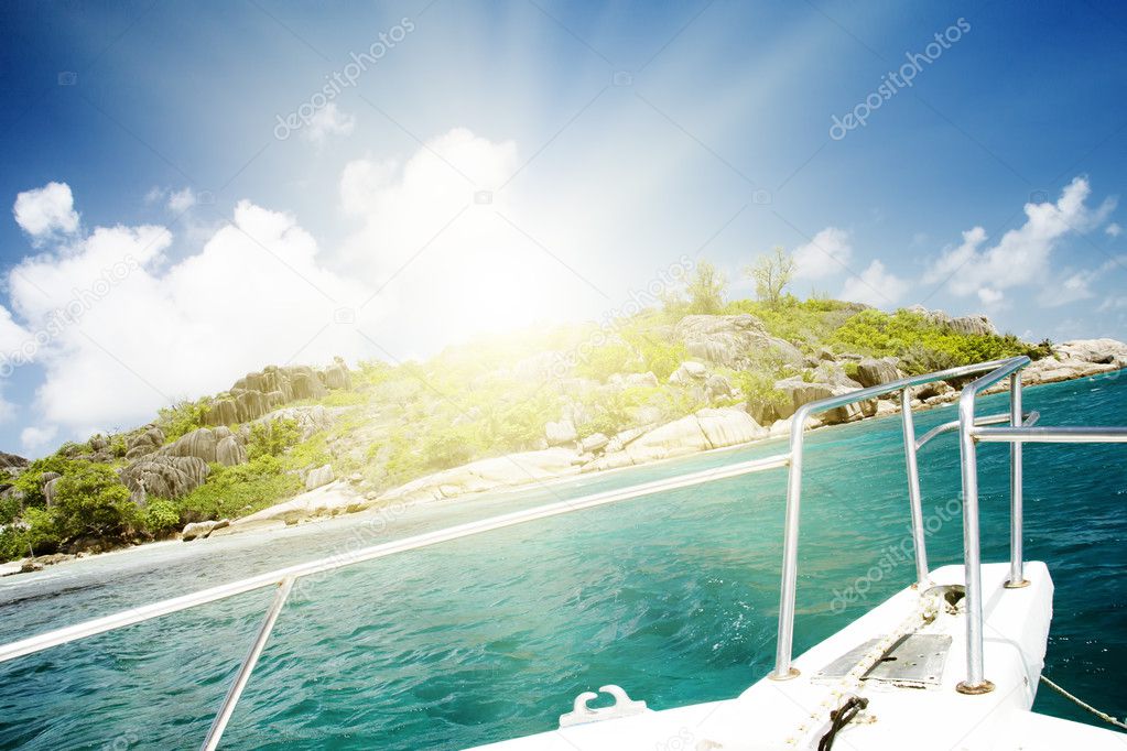 White yacht near rocky coast of seychelles.