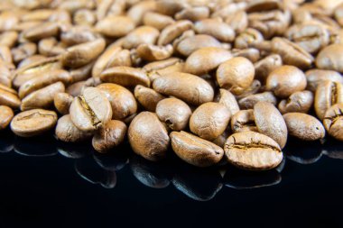 A close up of coffee beans on reflective black background