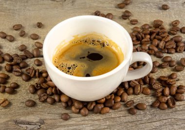 A cup of coffee and coffee beans on wooden board