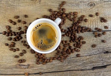 A cup of coffee and coffee beans on wooden board