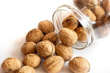 Whole solid walnuts in a jar on white background