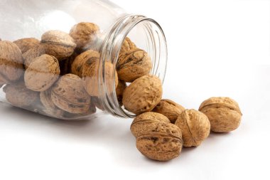 Whole solid walnuts in a jar on white background