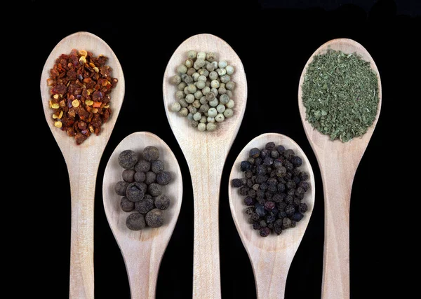 Spices in wooden spoon isolated on black background