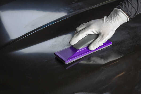 Grinding car body parts with a manual sanding planer before painting.