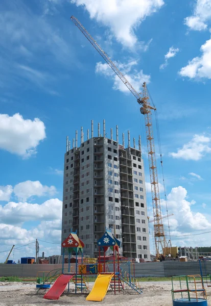 Moderní budova ve výstavbě s jeřábem a hřiště — Stock fotografie