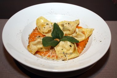 Beyaz tabakta sos ve parmesan tortelloni