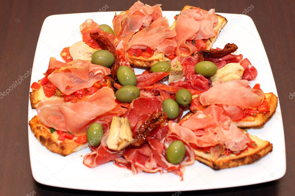 Closeup of the bruschetti with ham and olives on a plate at restaurant