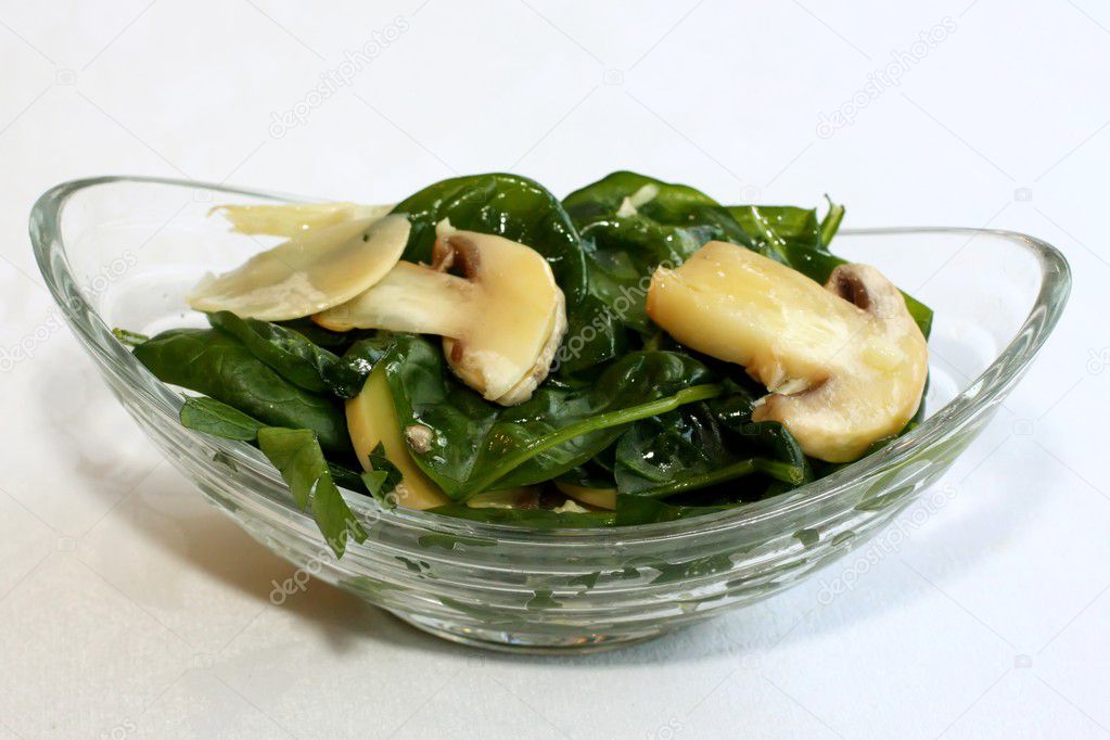 Fresh salad with spinach and mushrooms on glass bowl