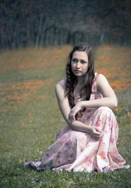 Задумчивая девушка сидит на траве — стоковое фото