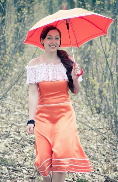 Va fille dans une robe orange avec un parapluie — Photo