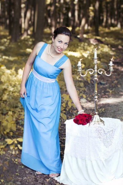 Sonriente chica toma un ramo de rosas rojas de una mesa con una ca — Foto de Stock