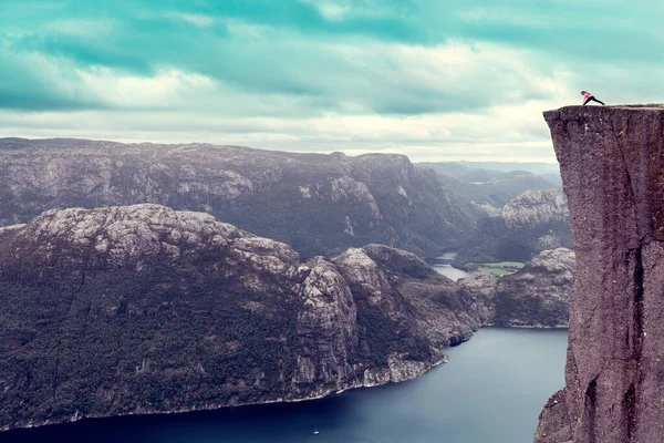 Günün şafağındaki kız popüler dağın tepesinde yoga yapıyor. Preikestolen.