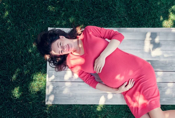 Gravid Flicka Klädd Rosa Klänning Liggande Ett Gräs Och Håller — Stockfoto