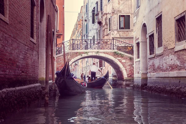 The gondolier floats on a narrow canal in Venice under the bridge