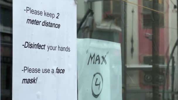 Warning sign telling about social distancing on cafe window during coronavirus pandemic — Stock Video