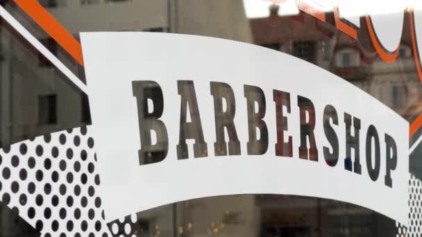 Weißes Friseurschild am Fenster mit europäischer Stadtstraße in Reflexion — Stockvideo