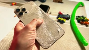 Erkek el ele tutuşması tamamen kırılmış arka paneli kırılmış akıllı telefon.