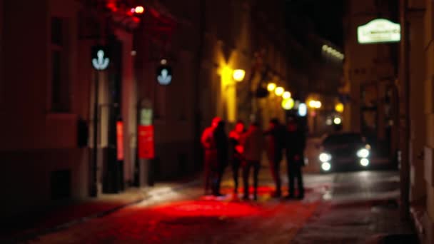 Groep toeristen chatten buiten een bar met rode lichten bij de ingang — Stockvideo