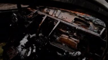 İçinde yanmış terk edilmiş bir arabanın görüntüsü var.