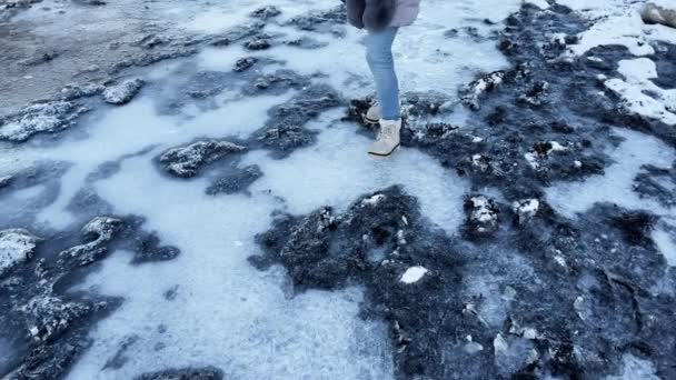 Γυναίκα περπατά στην παγωμένη παραλία πατώντας στον πάγο και κάνοντάς την να σπάσει — Αρχείο Βίντεο
