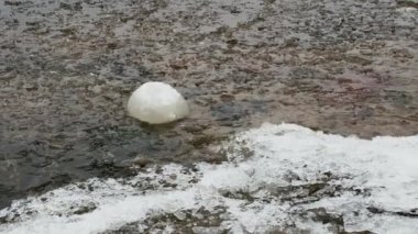 İlkbaharda nehir kıyısında eriyen küresel buz kütlesi