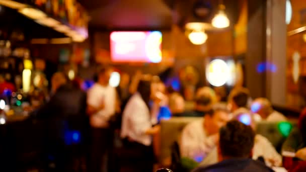 Oskärpa: Människor som dricker, äter och spelar pubspel i baren på natten — Stockvideo