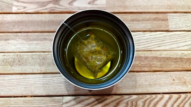 Gelas panas dengan kantong teh hijau di dalam meja kayu - Masih ditembak — Stok Video