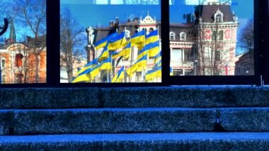 Pencereye yansıyan birçok Ukrayna Bayrakları mavi gökyüzünde rüzgarda dalgalanıyor