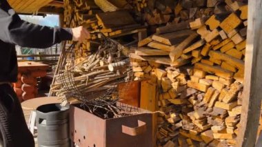 Erkek çiftçi, Ukrayna 'nın bir köyünde büyük bir odun duvarından kesilen odunları bir taşıma kutusuna koyar.