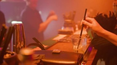 Bartenders dancing in nightclub illumination while party people chilling at bar table