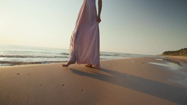 Suis dolly out : Jolie femme en robe longue marchant sur sable mouillé sur fond de mer coucher de soleil — Video