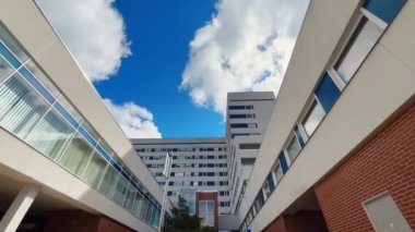 Modern bir merkez hastane binası olan hızlı hareket eden bulutlar ön planda geniş açılı çekim yapıyor.