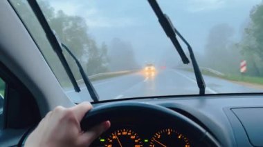 4K 'nin dışındaki bir otoyolda bir adam araba kullanırken silecekler çalışıyor.