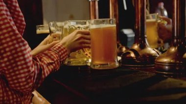 Garson, gece barda servis yapmak için büyük bardakta bira alıyor.