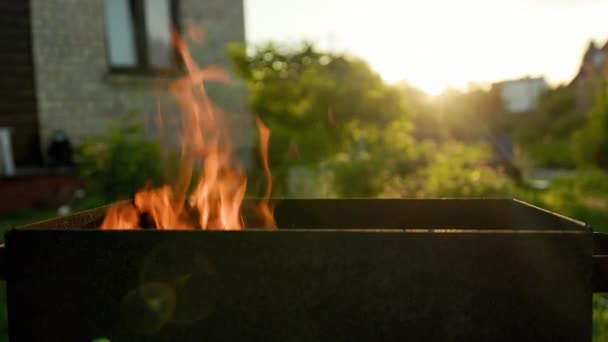 Tűz és láng égő grill előtt főzés naplementekor a vidéki házban