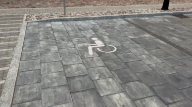 City disabled parking lot white sign over brick pavement real time