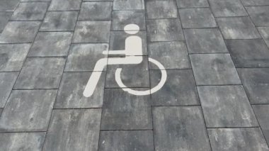 Large disabled parking lot white sign over brick pavement real time