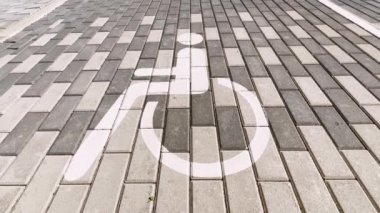 PAN UP: Establishing shot of a disabled sign on pavement at mall real time