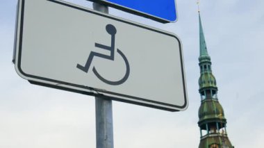 Panning up close view: Disabled parking sign on a pole at an old town in Europe real time
