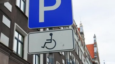 ORBIT: Disabled parking sign on a pole over dark building at an old town in Europe real time
