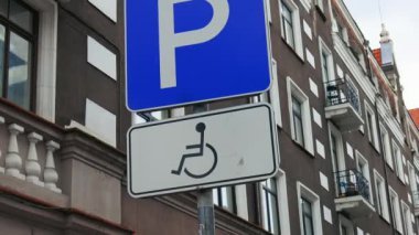 Disabled parking sign on a pole over dark building at an old town in Europe real time