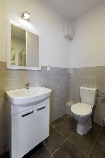 Moderne betegelde badkamer met wc, wastafel en spiegel — Stockfoto
