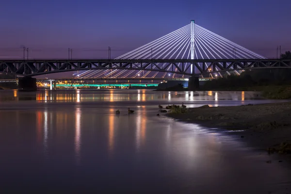 Nachts beleuchtete Brücke, die sich im Wasser spiegelt — Stockfoto