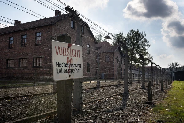 Voorzichtig, hoog-voltage, gevaar teken in auschwitz ii-birkenau kamp in brzezinka — Stockfoto