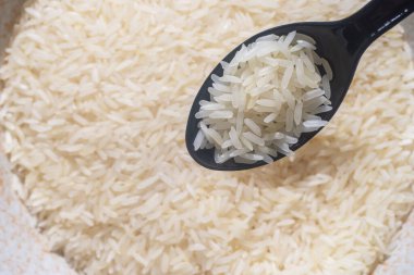 Tayland yasemin pirincini siyah kaşıkla yakın plan çek. Tayland kökenli bir pirinç türüdür. Pandan yaprağı gibi kokuyor. Tayland pirincini tüm dünyada bilinen bir ihracat ürünü yapan pirinç çeşididir.